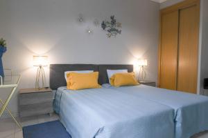 um quarto com uma cama azul e 2 almofadas amarelas em Agua Viva by Umbral em Albufeira