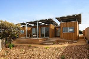 a wooden house with a porch and stairs to it at Eco Shipping Container Home in Kilcunda