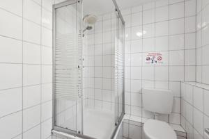 a white tiled bathroom with a shower and a toilet at Worker Apartment Goch in Goch