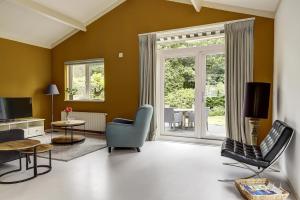 a living room filled with furniture and a large window at Luxe boshuisje op kleinschalig park op de Veluwe in Putten