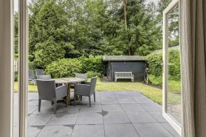 a patio with a table and chairs and a yard at Luxe boshuisje op kleinschalig park op de Veluwe in Putten