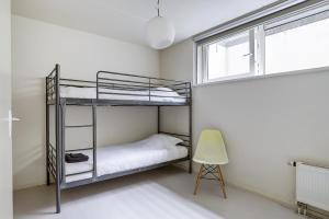 a bedroom with two bunk beds and a chair at Luxe boshuisje op kleinschalig park op de Veluwe in Putten +7 photos
