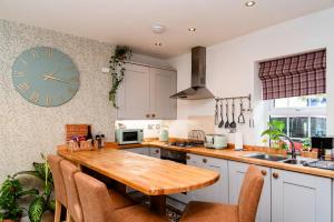 a kitchen with a wooden table and a clock on the wall at Cosy Days Cottage in Skipton