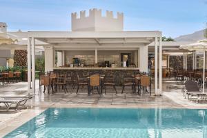 an outdoor patio with a bar and a pool at Lindos Royal Resort in Líndos