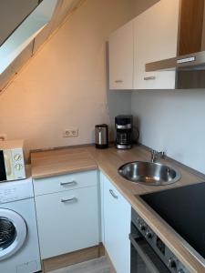 a small kitchen with white cabinets and a sink at Studio 29 in Oberhausen