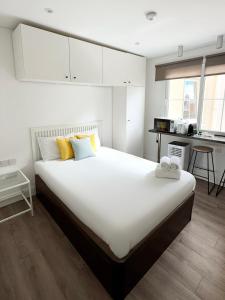 a bedroom with a large white bed with yellow pillows at Stylish City Centre Studio - Grand Central House in Gibraltar