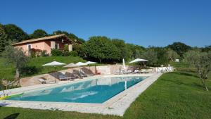 a swimming pool with chairs and umbrellas next to a house at Casale Citerno in Bolsena