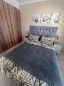 a bedroom with a large bed with a blue headboard at The Jade Somerset West Beachfront Apartment with Pool & Mountain Views in Cape Town +17 photos