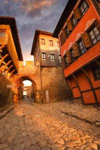 a stone street with buildings and an archway at Харизма in Hisarya
