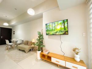 un salon avec une télévision à écran plat au mur dans l'établissement Elegant BGC Condo Across Mitsukoshi Mall #upt27p, à Manille