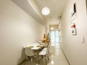 une salle à manger avec une table et des chaises blanches dans l'établissement Elegant BGC Condo Across Mitsukoshi Mall #upt27p, à Manille