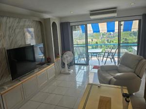 ein Wohnzimmer mit Fernseher, Couch und Tisch in der Unterkunft Villa Germania in Jomtien Beach