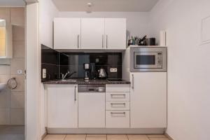 a kitchen with white cabinets and a microwave at Villa Waldpark in Dresden