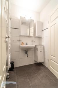 een witte badkamer met een wastafel en een spiegel bij Ferienwohnung 1 im 'BÖTTCHER HUUS' in Langeoog