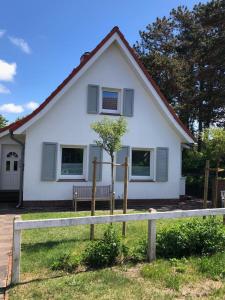 una casa blanca con un banco delante en Residenz 'NORDLICHT', en Langeoog