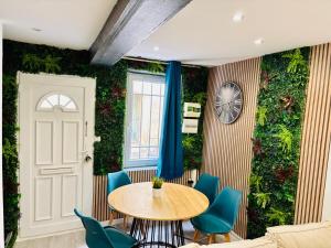 a dining room with a green wall with a table and chairs at Sereni house jacuzzi in Narbonne