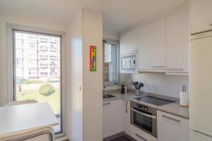 a kitchen with white cabinets and a large window at Apartamento Holidea Parque las Llamas in Santander