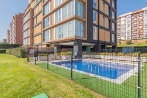 a fence around a swimming pool in front of a building at Apartamento Holidea Parque las Llamas in Santander