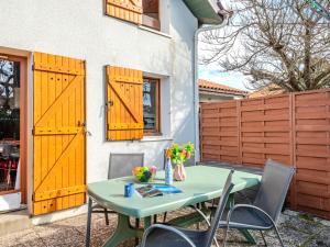 d'une terrasse avec une table, des chaises et des portes jaunes. dans l'établissement Apartment Les Landaises-5 by Interhome, à Mimizan-Plage