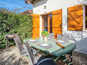 une table verte avec des chaises et une clôture avec des portes en bois dans l'établissement Apartment Les Landaises-5 by Interhome, à Mimizan-Plage