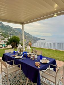 a table with a blue table cloth and chairs and the ocean at Residenza San Luca Praiano in Praiano
