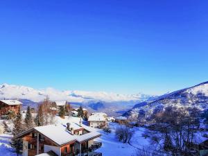 a house covered in snow with mountains in the background at Apartment Arnica 16 by Interhome in Nendaz