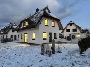 una casa blanca con luces encendidas en la nieve en Ferienhaus "Rugard" in Dranske, en Dranske
