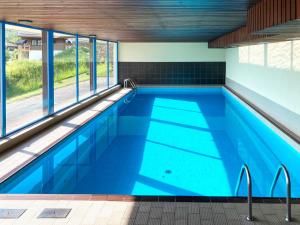 a swimming pool with blue water and windows at Apartment Arnica 16 by Interhome in Nendaz