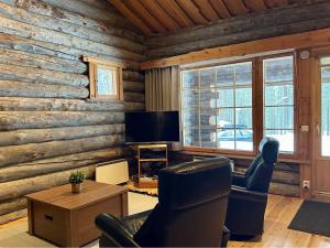 a living room with wooden walls and chairs and a television at Holiday Home Sallan savu a by Interhome in Salla