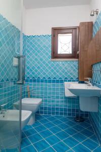 un bagno piastrellato blu con un water e un lavandino di Marina Maria a Murta Maria