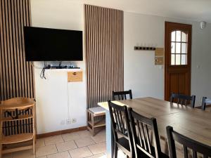 a dining room with a table and a flat screen tv at Cacatoès in Saint-Aignan