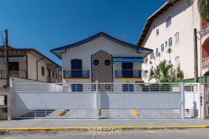 a white house with a fence in front of it at Elegante Apto a 260m da Praia Grande BTI003 in Ubatuba