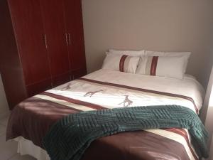a bed with a green blanket on top of it at TnK Abode Apartments in Kathu