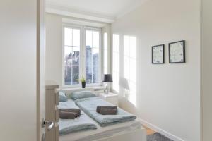 Una cama en una habitación blanca con ventana. en YOURAPART Piwna Luxury Apartment, en Gdansk