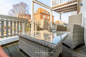 balcón con mesa de cristal y sillas de mimbre en Fewo Meerluft nur wenige Minuten vom Hafen und Strand entfernt, en Laboe