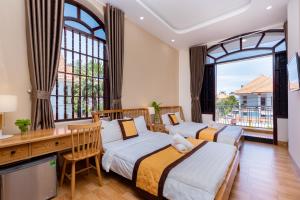 two beds in a room with a desk and windows at Hoàng My Villa Bãi Sau Vũng Tàu in Vung Tau +139 photos