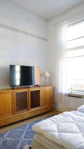 a bedroom with a flat screen tv on a wooden cabinet at Wanha Rovastiinna, SELF-SERVICE Unique city apartment in Vaasa