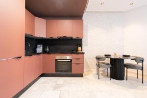 a kitchen with pink cabinets and a table with chairs at Studio Ferme Bretonne, Bien Desservi & Salle Gym in LʼOasis +4 photos