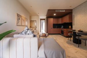 a living room with a white couch and a kitchen at Studio Ferme Bretonne, Bien Desservi & Salle Gym in LʼOasis