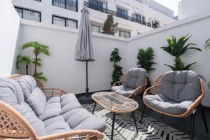 a patio with chairs and tables and an umbrella at Studio Ferme Bretonne, Bien Desservi & Salle Gym in LʼOasis