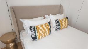 a white bed with four pillows on it at Flat with garage and balcony with view to a garden in Vila Nova de Gaia