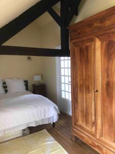 莫龙Bakers Cottage near broceliande forest的一间卧室配有一张床和一个大型木制橱柜