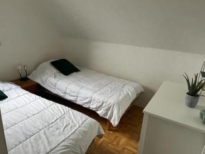 a bedroom with two beds with white sheets and a plant at Maison paisible avec jardin à Houlgate in Houlgate