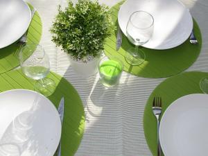 una mesa con platos verdes y copas de vino. en Paraíso Azul, en Eira do Chão