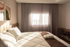 een slaapkamer met een wit bed en een raam bij KEEP SUÍTES HOTEL in Taubaté