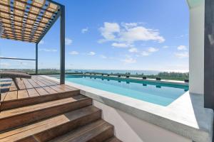 a swimming pool with stairs and a view of the ocean at Suite Jungle Studio with Views Walk Everywhere in Playa del Carmen