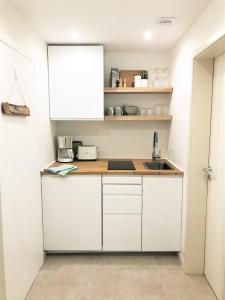 Una cocina con gabinetes blancos y un fregadero. en Lifestyle Apartment, en Schwabach