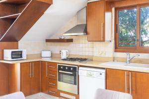 a kitchen with wooden cabinets and a stove top oven at Villa Sunlove in Peyia