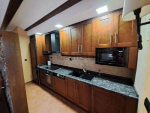 a kitchen with wooden cabinets and a sink and a microwave at Apartamento Casa Florentina in Albarracín