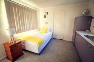 a small bedroom with a bed with a yellow blanket at Mt Isa City Motel in Mount Isa